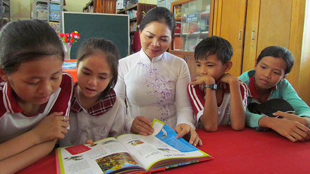 Cô Giang hướng dẫn các em học sinh lớp 3 đọc sách trong tiết đọc thư viện tại Trường tiểu học Ngũ Hiệp 1 - Ảnh: Bảo Châu